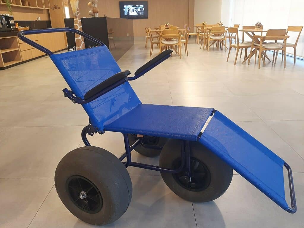 Cadeira anfíbia do hotel Brisa Maragogi. Ao fundo, tem mesas e cadeiras, um balcão à esquerda e uma TV suspensa na parede