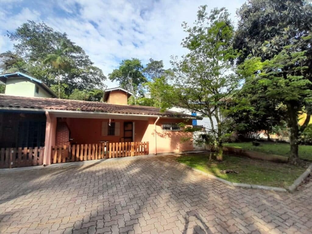 Lado de fora da Aconchego casa, Ela possui um cercadinho, uma área com churrasqueira e fica perto de um gramado com algumas árvores.