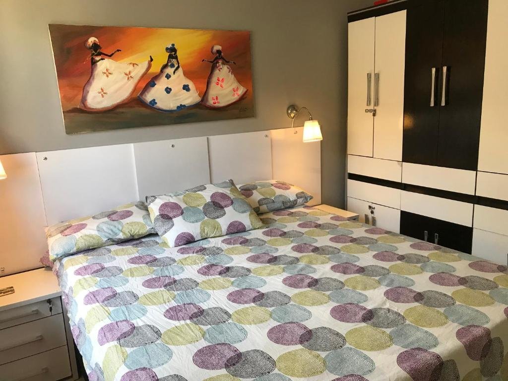 Quarto da Aldeia St. Sebastien 25. Uma cama de casal no meio, uma cômoda com um abajur de cada lado. No lado direito da cama um guarda-roupa. Foto para ilustrar post sobre pousadas em Arembepe.