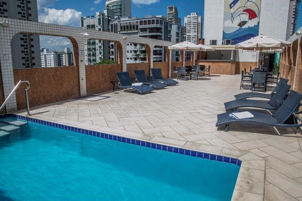 Piscina do Atlantico Inn Apart Hotel na cobertura da propriedade, com um deck grande que conta com espreguiçadeiras e mesas com cadeiras e guarda-sóis