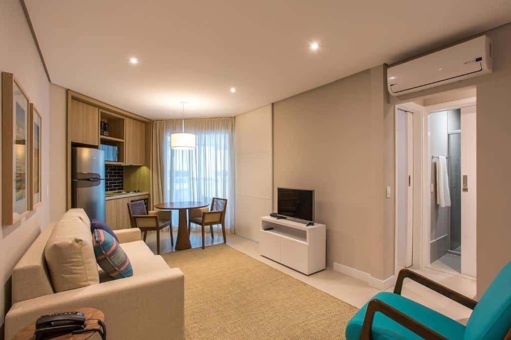 Sala do Book Santos Apartamentos Estanconfor com uma pequena sacada, uma mini cozinha, um sofá com dois lugares, uma televisão e um ar-condicionado de teto