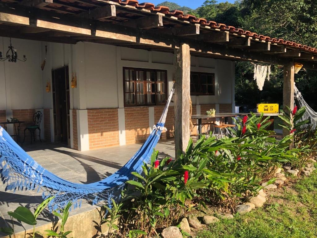 Casa de praia em Paúba perto de cachoeira. Há um jardim, rede de descano e uma varanda coberta pelo telhado da casa.