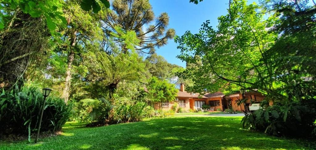 Entrada da CASA GOLDONI GRAMADO 3 Quartos, com um enorme jardim, um gramado extenso com árvores e arbustos, para representar airbnb em Gramado