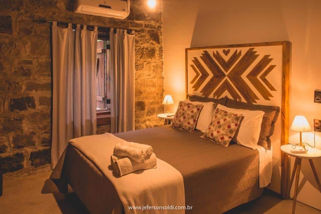 quarto da Casa Vêneto no Vale dos Vinhedos com cama de casal e décor em tons terrosos