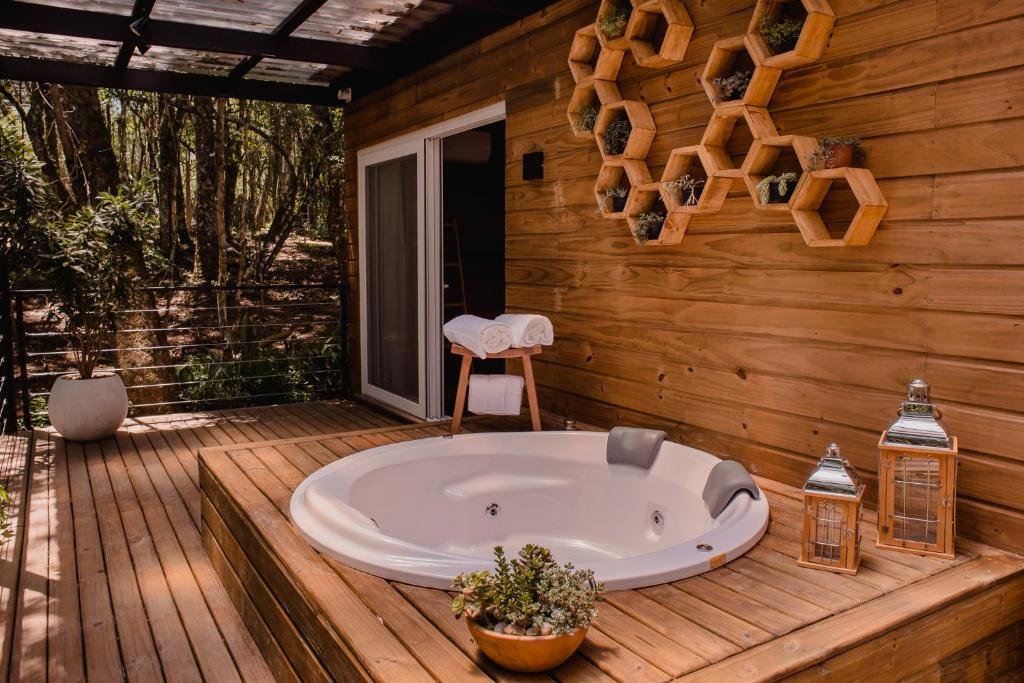 Uma hidromassagem cercada por um extenso deck na Vila Nambu, com toalhas e alguns vasos de flor ao redor