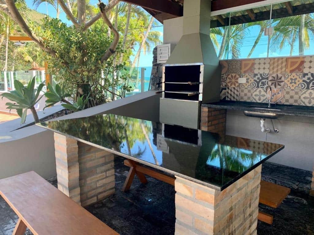 Churrasqueira e área de lazer no Porto Paúba Flat 116. Há uma pia, e ao lado dela há uma churrasqueira. No centro há uma mesa com bancos.