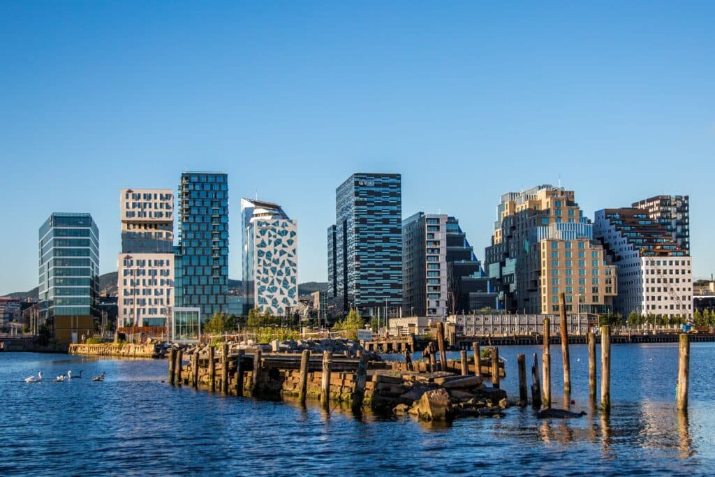 Vista da cidade Oslo, Norway com vários prédios um rio em frente a cidade e céu azul.