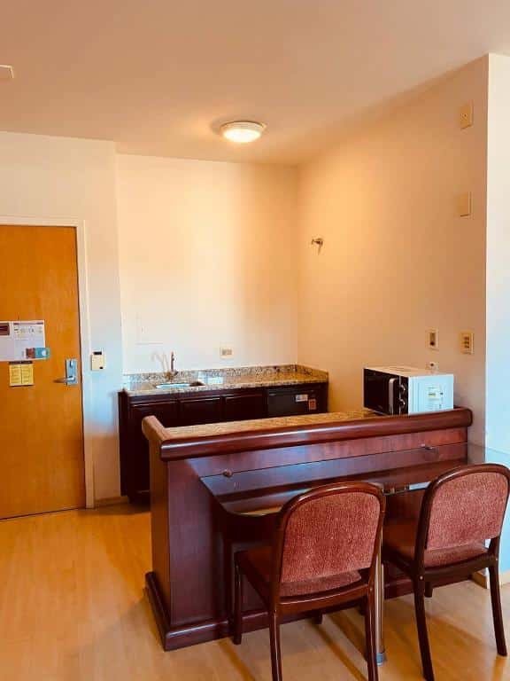 Cozinha do Apart-hotel Mercure Prinz com um balcão de pedra, um microondas em cima do balcão e duas cadeiras estofadas em frente ao balcão.
