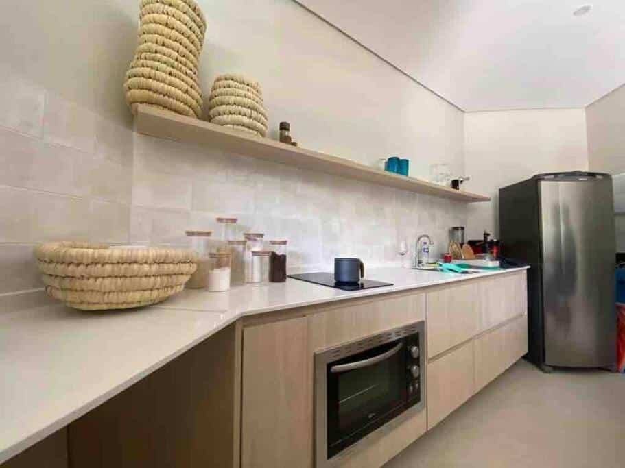 Cozinha da Praia do Engenho – Apart Lindo e Novíssimo 30m da praia com balcão do lado esquerdo da imagem com forno e fogão e mais a frente a geladeira.