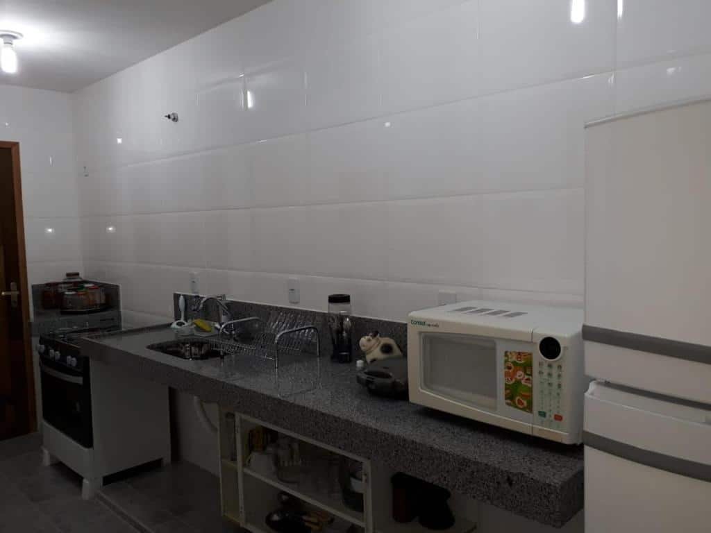 Cozinha do Thiferer Hostel. No canto direito é possível ver um pouquinho da geladeira, no meio há um balcão com pia, torneira, microondas e no lado esquerdo está o fogão.