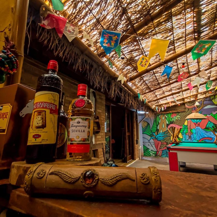 Área compartilhada do Efferus Hostel com mesa de sinuca, teto rústico de palha e uma parede com desenhos coloridos