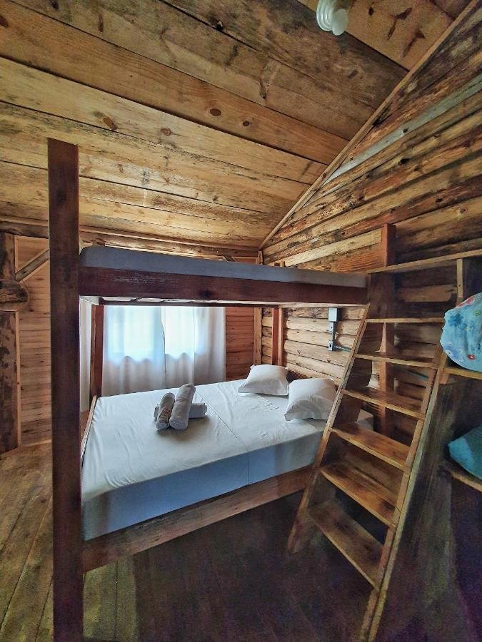 Um quarto rústico em estilo cabana na Fazenda Invernada Grande Turismo Rural, com paredes e teto de madeira, dispõe de um beliche com uma cama inferior bem arrumada e toalhas enroladas em cima.