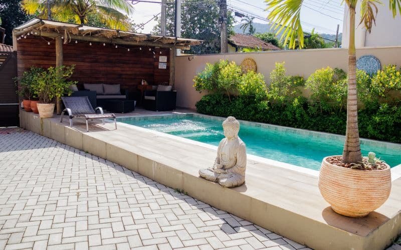 Piscina do Flats de Sumatra. Ela é retangular e está em um espaço com sofás e uma espreguiçadeura.