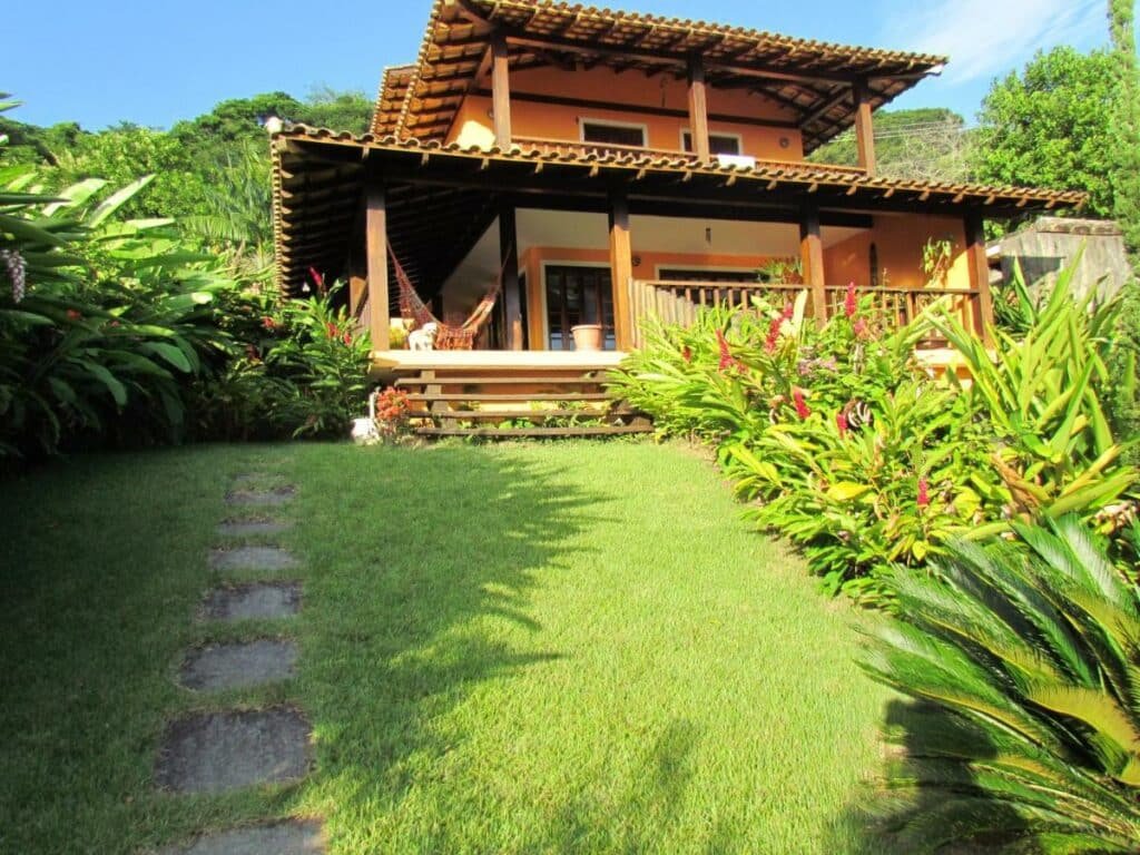 Frente da Casa Praia de Santiago durante o dia com jardim a frente e ao fundo a propriedade. Representa airbnb na praia de Santiago.