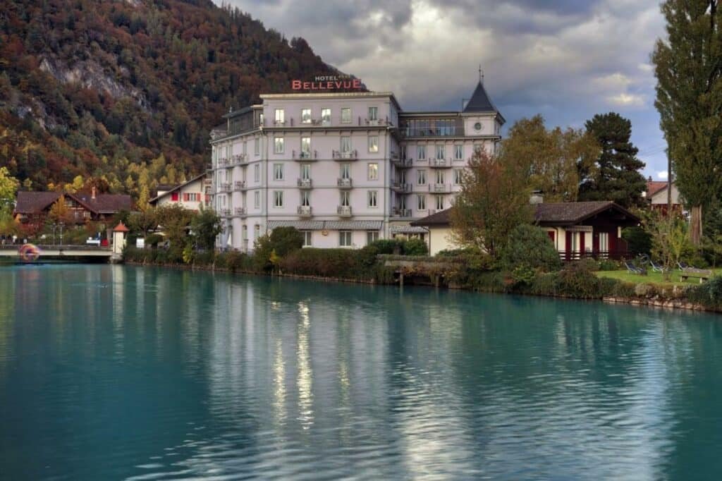 Frente do Boutique Hotel Bellevue durante o dia com lago a frente e ao fundo o hotel.