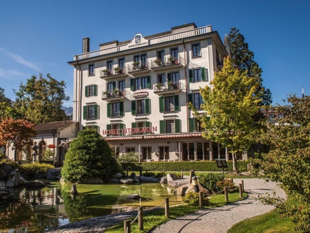 Frente do Hotel Interlaken durante o dia com um lado do lado esquerdo da imagem e ao fundo a estadia.