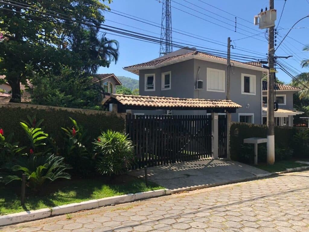 Frente do Doce Lar Toque Toque Grande durante o dia com portão e muro a frente e ao fundo a casa.