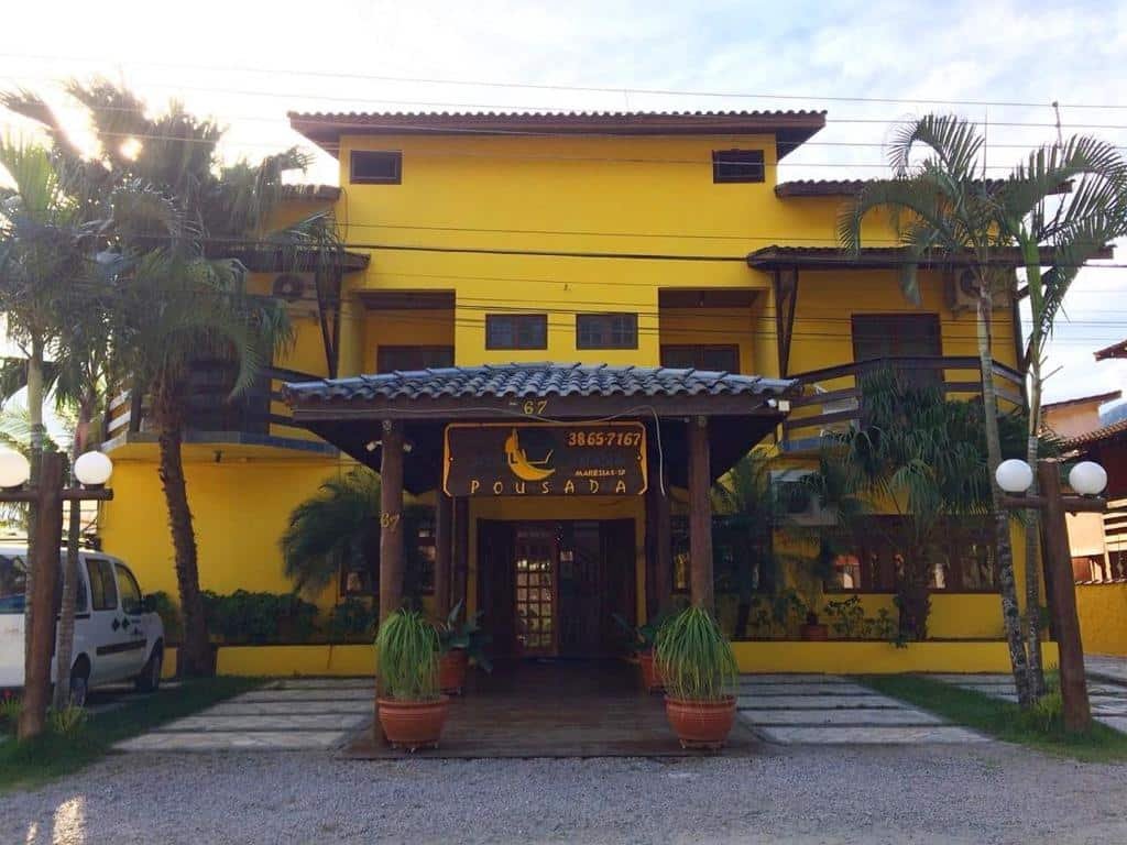 Frente da Azul Banana com cor amarela, janelas e portas de madeira e vasos de plantas na entrada.