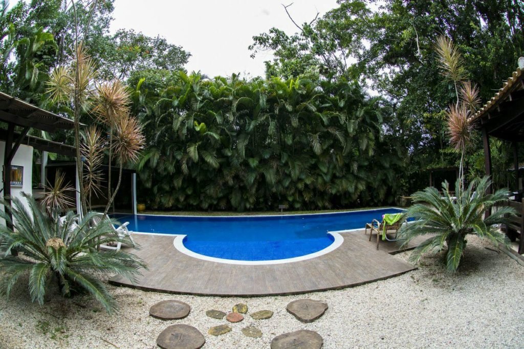 Piscina envolta por vegetação na Guest House da Lui