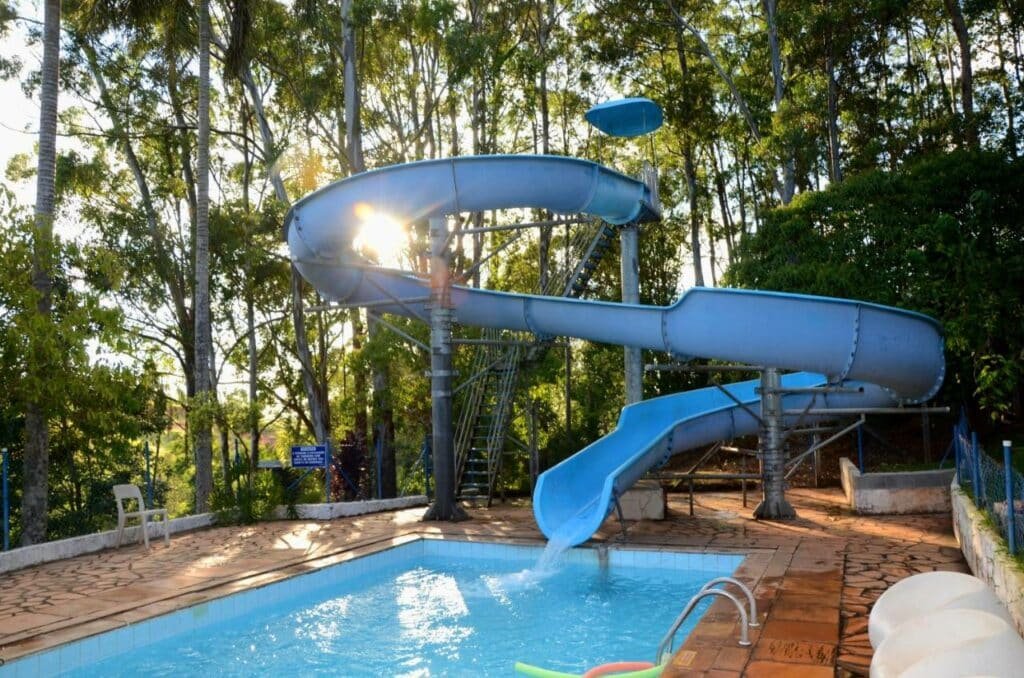 Escorregador que leva para a piscina no Hotel Akropolis com árvores ao redor do deck