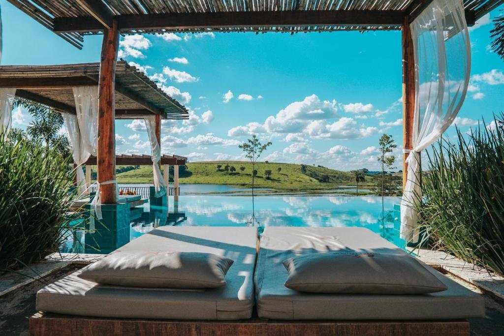 Vista da parte externa do Hotel Chalé Capitólio com vista para piscina e as montanhas, um local bem amplo, com bangalôs e sofás para se deitar