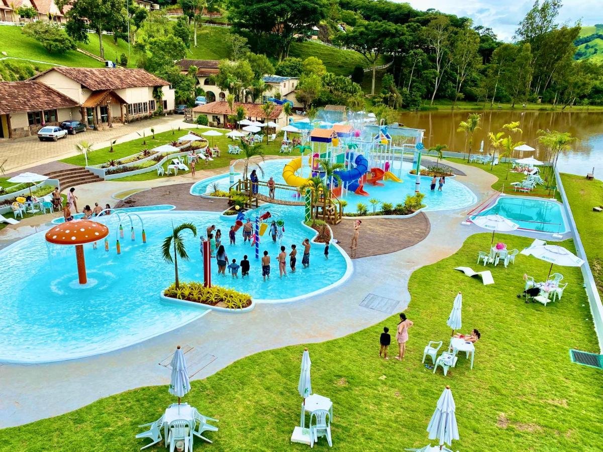Um parque aquático ao ar livre no Hotel Fazenda Vista Alegre conta com piscinas infantis, toboáguas, um parque aquático e pessoas aproveitando diversas atividades em um dia ensolarado.