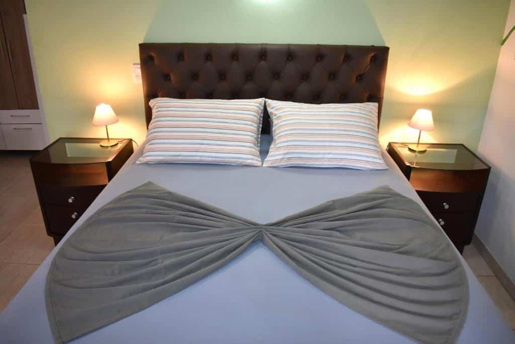 Quarto do Hotel Pousada Rancho Fundo. Uma cama de casal como uma cômoda e um abajur de cada lado.