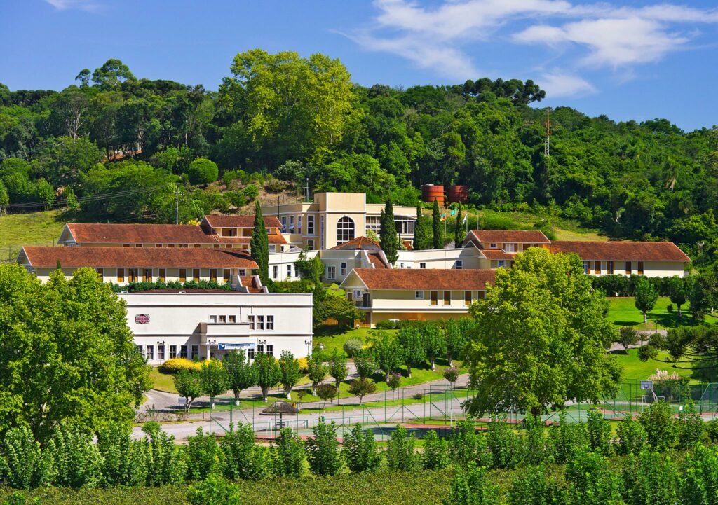 Área externa do Hotel Villa Michelon, com bastante verde em volta, incluindo árvores e arbustos