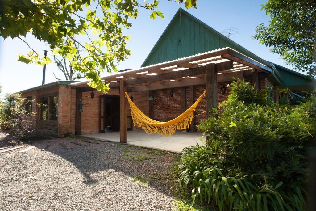 Casa da Belo Vale, em Garibaldi, no Vale dos Vinhedos, com parede de tijolinhos à vista, rede de descanso amarelo e telhado verde