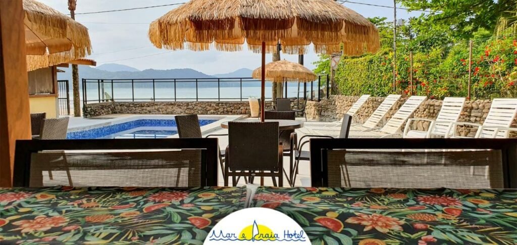 Piscina do Mar e Praia Hotel, virada para o mar, com muitas cadeiras e espreguiçadeiras ao redor
