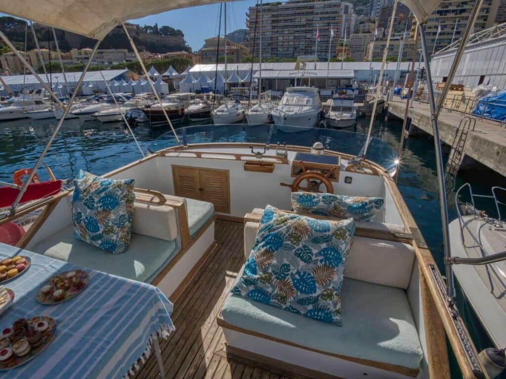 Iate do Monte-Carlo for boat lovers. Sofás e um mesinha de frente. Atrás a ponta do iate, com vista para outros iates o porto.