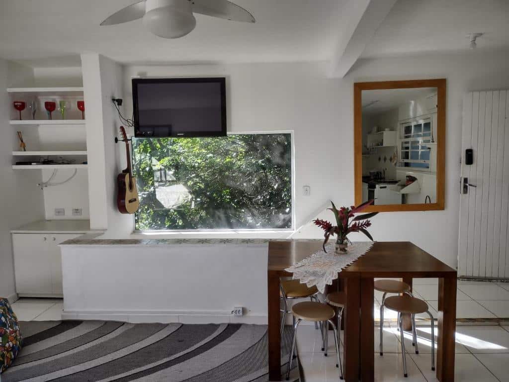 Casa O melhor pôr do sol de Paúba! O ambiente interno é aberto. Vemos de frente uma mesa com bancos, um espelho, uma TV, uma janela embaixo da TV e um armário de cozinha à esquerda.