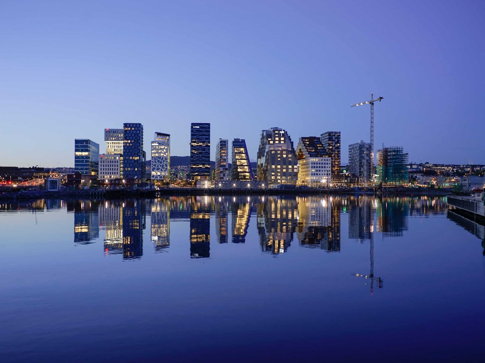 Vista da cidade de Oslo ao anoitecer com vários prédios e um rio a frente dos prédios. Representa hotéis em Oslo.