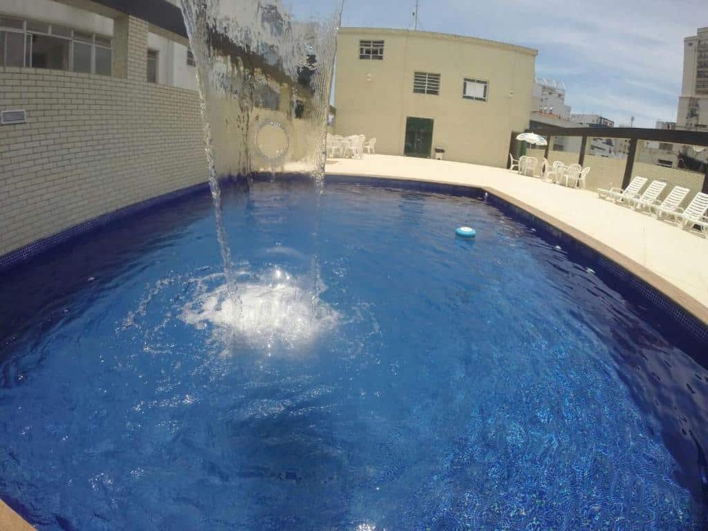 Piscina do Atlântico Golden Apart Hotel em um deck com algumas espreguiçadeiras brancas ao redor