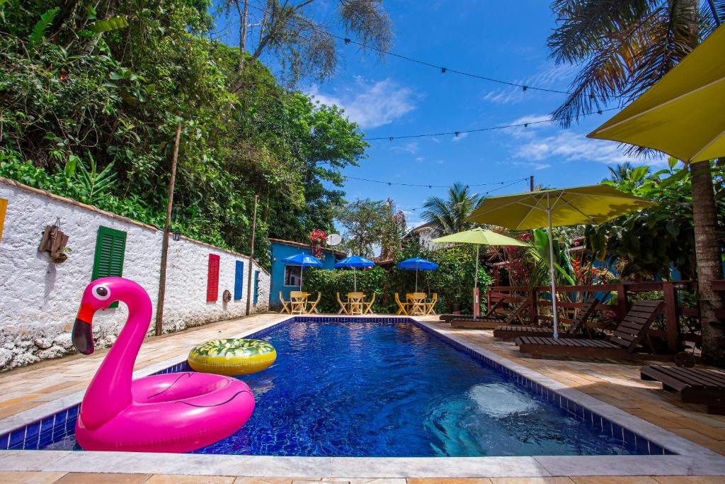 Vista da piscina da Pousada Villa Blu Maresias durante o dia com duas boias dentro da piscina, cadeiras do lado esquerdo. Representa pousadas na praia de Santiago.