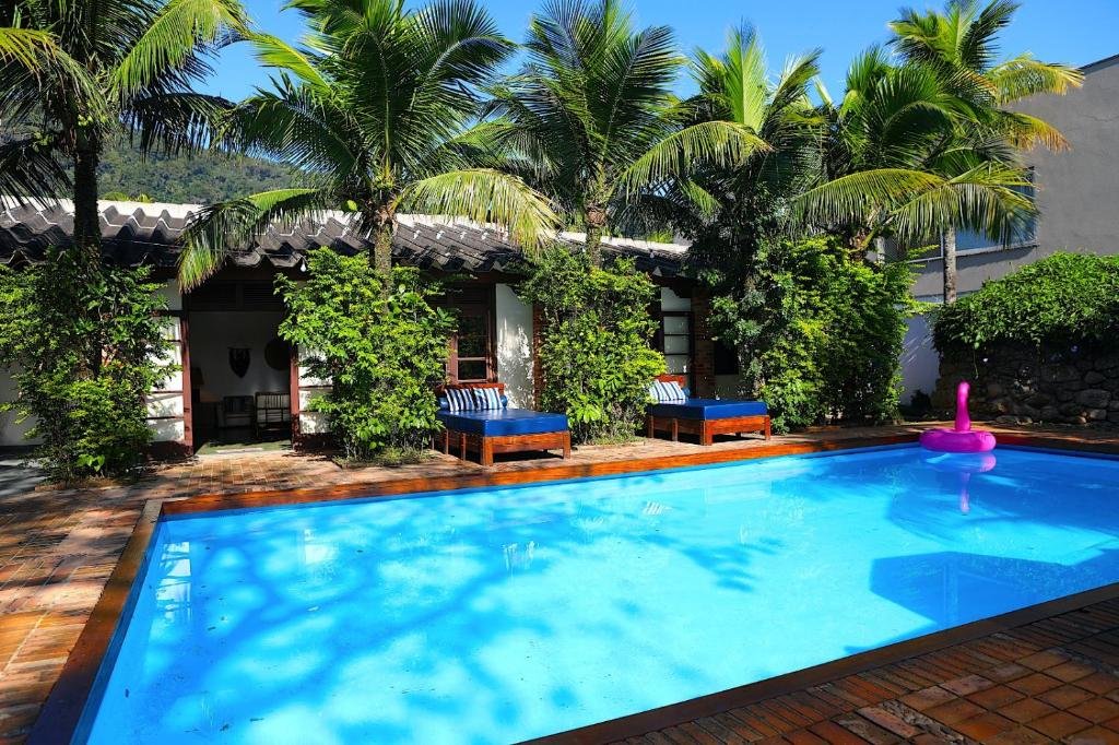 Piscina do Canto das Laranjeiras Beach Club Guaiuba com muito verde ao redor com árvores e arbustos, há também espreguiçadeiras no local