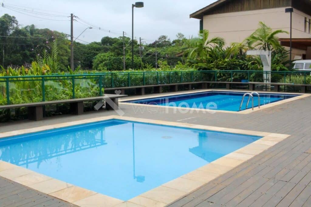 Piscina ao ar livre da Casa em Condomínio na Praia em São Sebastião durante o dia com piscina ao meio.