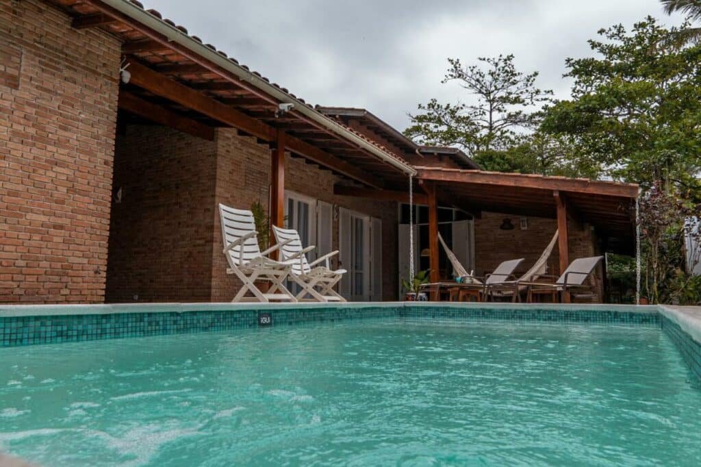 Piscina do Pousada Cocal da Praia com espreguiçadeiras e redes ao redor