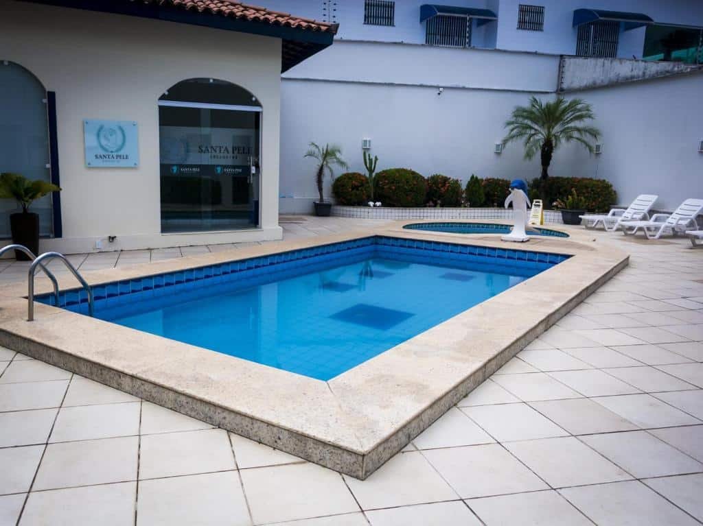 Piscina do Costa Atlantico Hotel com um deck pequeno com espreguiçadeiras brancas e algumas plantas, para representar hotéis em São Luís do Maranhão