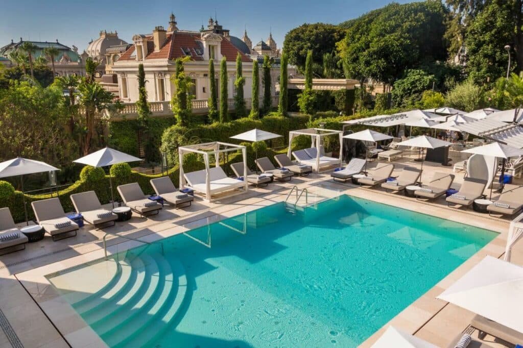 Piscina do Hôtel Métropole Monte-Carlo - The Leading Hotels of the World. Uma piscina no terraço com cadeiras de tomar sol e guarda-sóis ao redor.