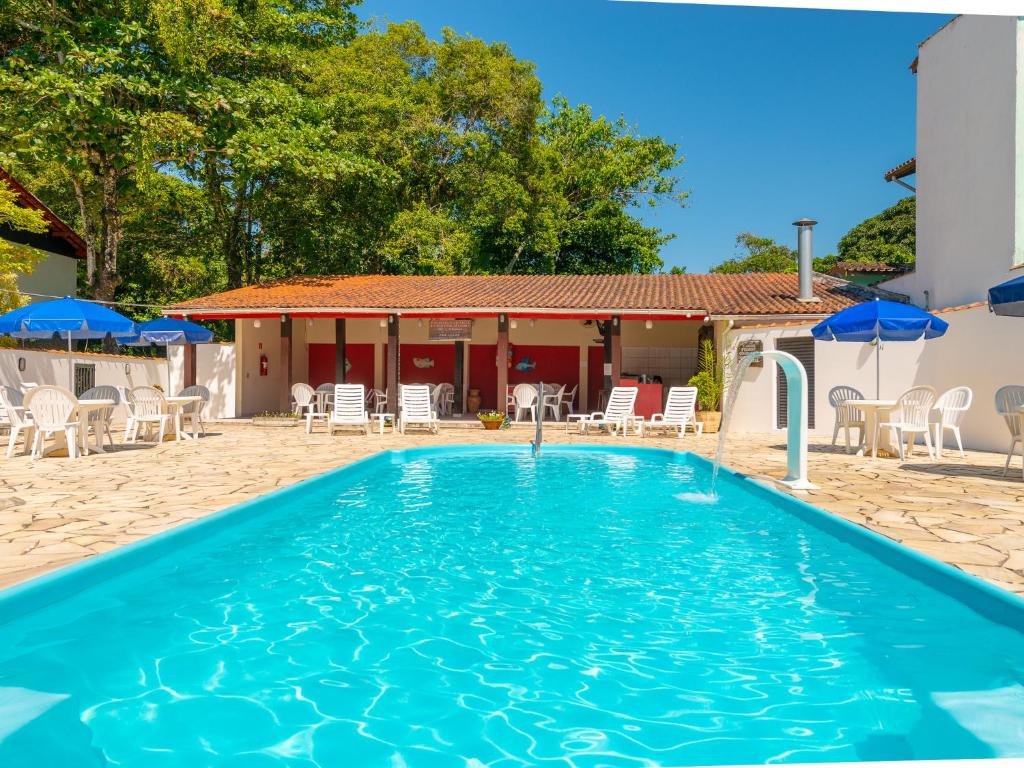Piscina em Hotel Saveiros na Praia do Lázaro, piscina ampla com uma pequena cascata, ao redor, muitas cadeiras, mesas e guarda-sóis