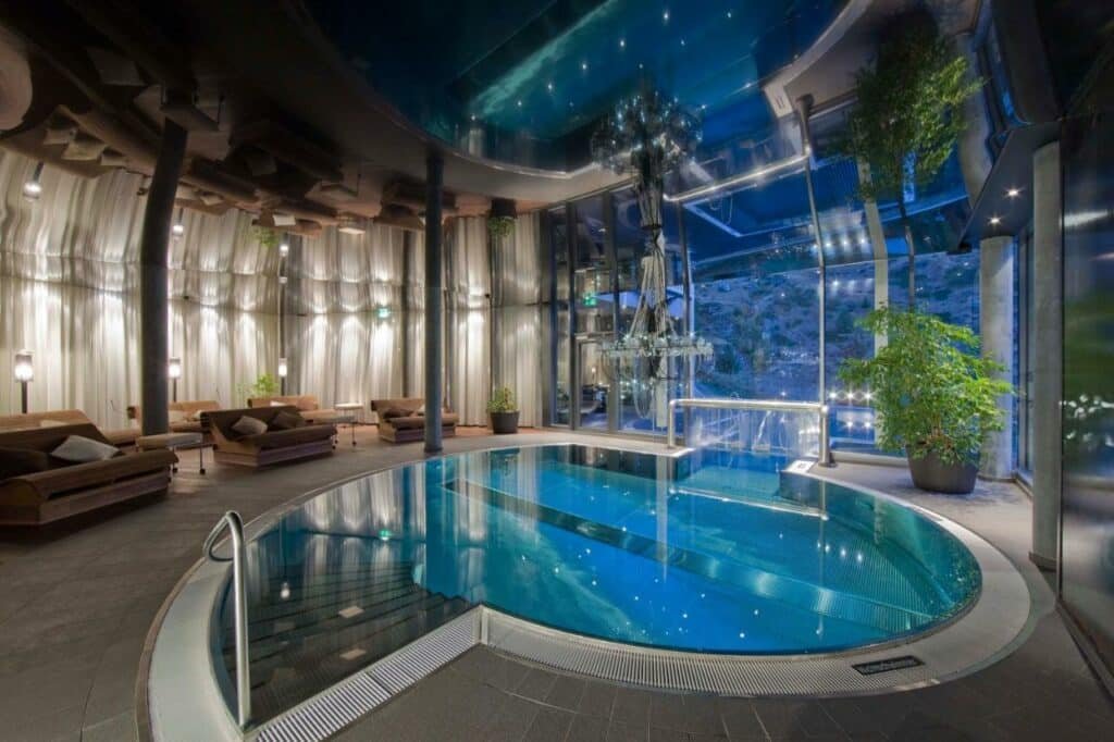 Piscina coberta do Matterhorn FOCUS Design Hotel com piscina do lado direito da imagem e do lado esquerdo sofás.