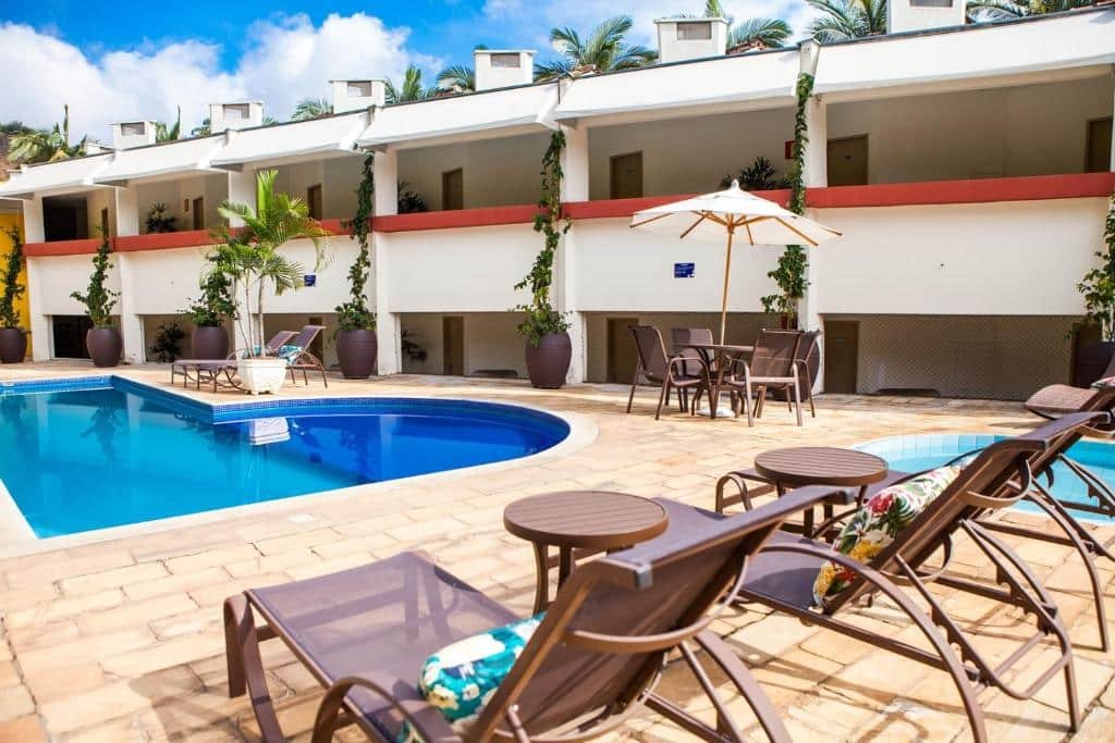 Área externa do Mundial Parque Hotel. No lado direito é possível ver uma pequena piscina redonda, no lado esquerdo há uma piscina maior em formato de L. No fundo estão as varandas dos quartos do hotel.
