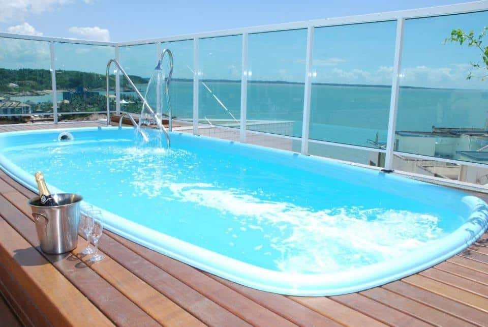 Piscina da Pousada Barlavento. Uma piscina no terraço, com um champagne e duas taças no lado esquerdo, No lado direito e no fundo, o vidro cercando a piscina, com vista para o mar.