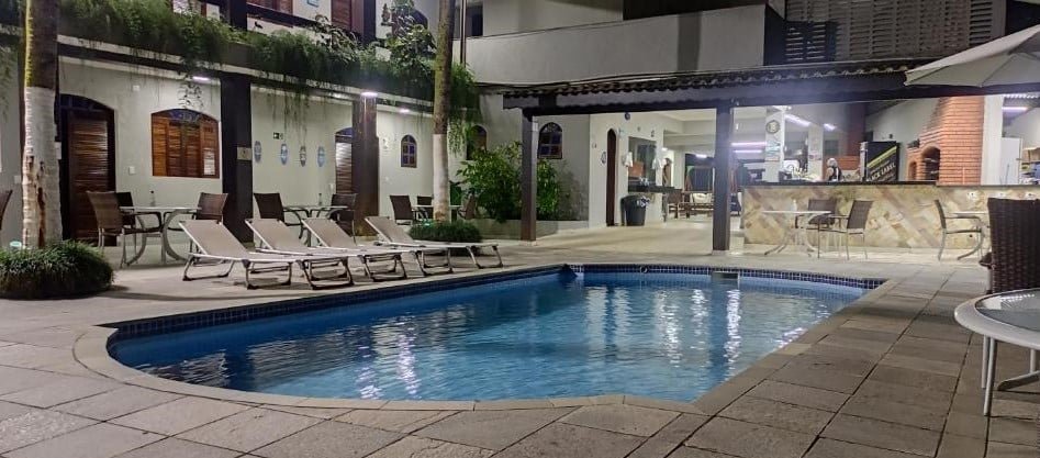 Piscina ao ar livre da Pousada do Vladimir. Cadeiras ao redor, atrás a pousada e um espaço com churrasqueira. Foto para ilustrar post sobre Pousadas em Boracéia.