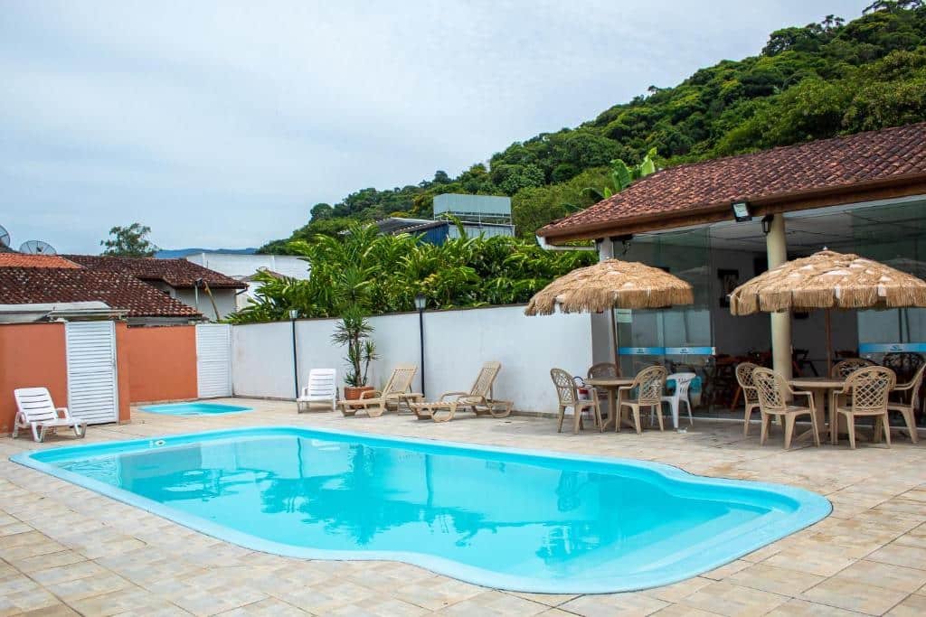 Piscina na Pousada Pescador, com cadeiras e mesas ao redor, para representar pousadas na Praia da Enseada em Ubatuba