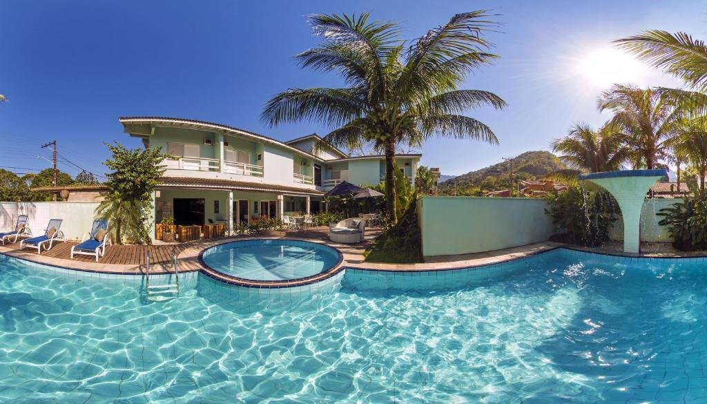 Vista da piscina da Toca da Praia durante o dia, com a piscina a frente e ao fundo a hospedagem.
