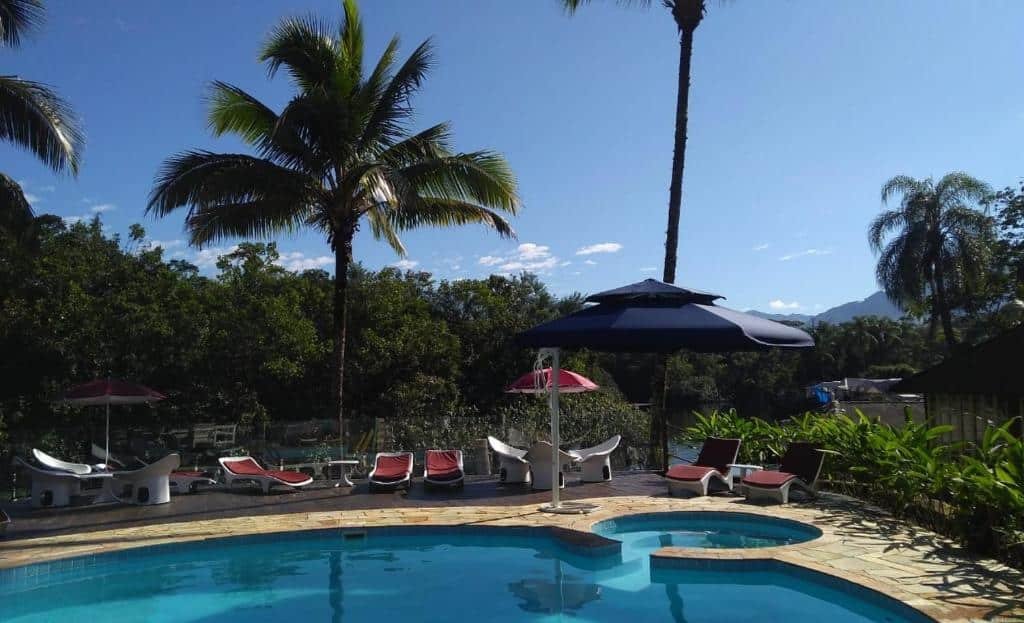 Vista da piscina da Pousada Una durante o dia com cadeiras do lado esquerdo com cadeiras. Representa pousadas na praia do Engenho.