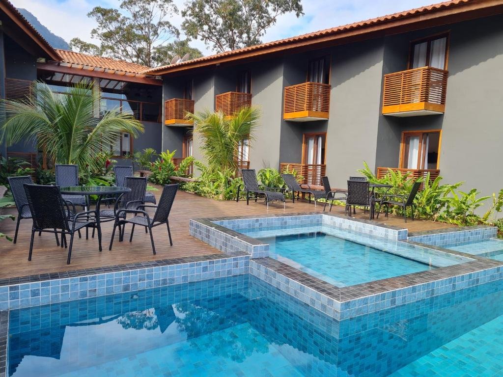 Vista da piscina da Pousada Vila Ipuan, com cadeiras com mesas em frente a hospedagem. Representa pousadas em Paúba
