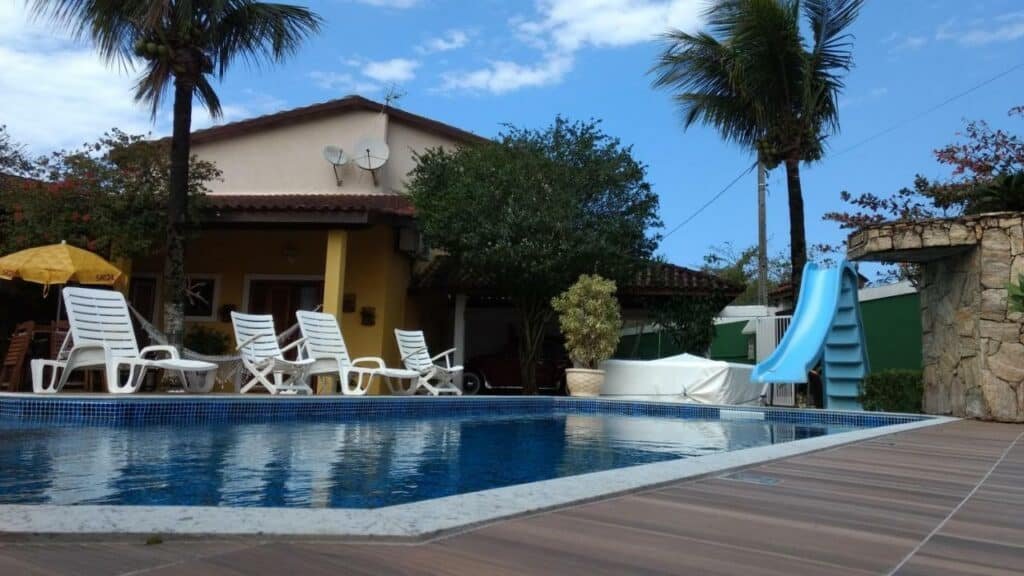 Piscina na Pousada Villa Virgínia Guarujá com um deck com espreguiçadeiras e um escorregador